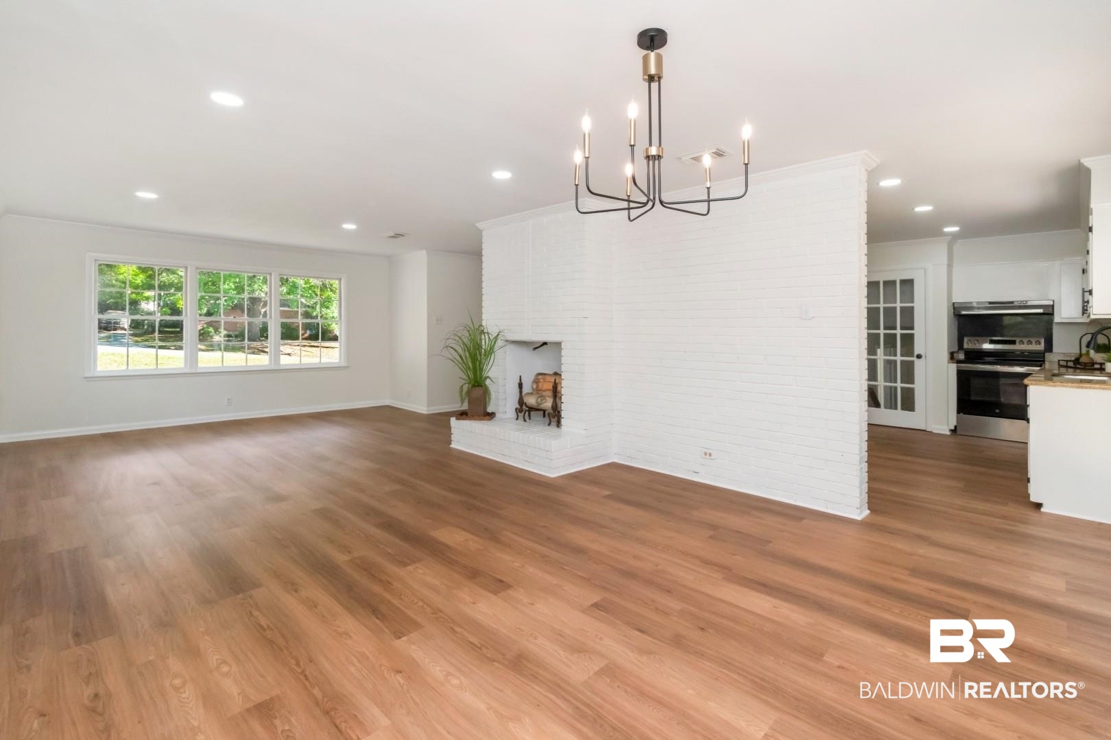 115 Pineridge Road Daphne, AL 36526 - Photo 9 of 34 Unfurnished living room featuring brick wall, baseboards, a notable chandelier, and light wood-style floors
