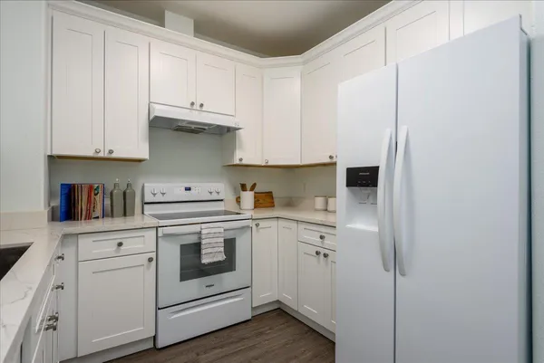 a kitchen with cabinets appliances and a wooden floor