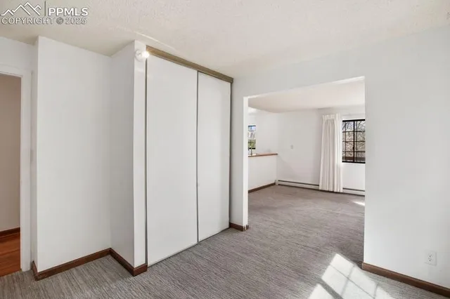 a view of an empty room with wooden floor and a bathroom