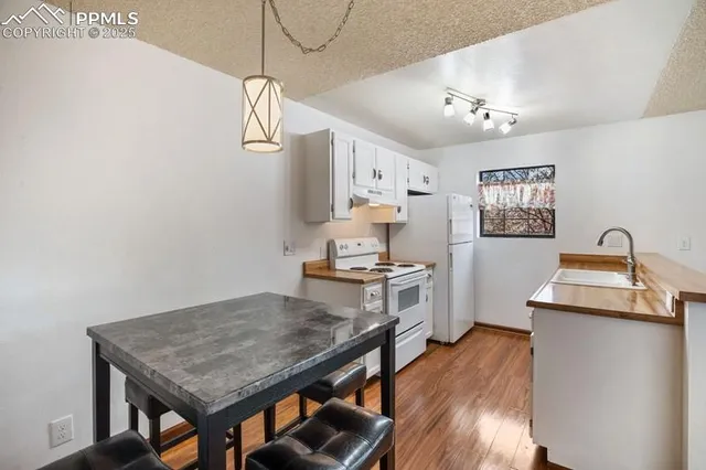 a kitchen with stainless steel appliances granite countertop a sink dishwasher a stove top oven a dining table and chairs with wooden floor