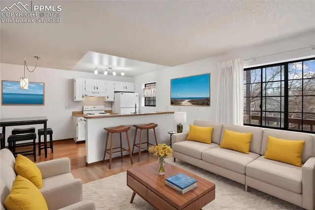 a living room with furniture kitchen view and a large window