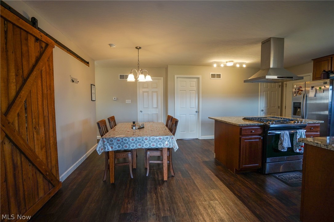 1325 County Line Road Hopewell, OH 43746 - Photo 5 of 45 Dining room featuring a barn door, dark wood-style flooring, and hanging lights