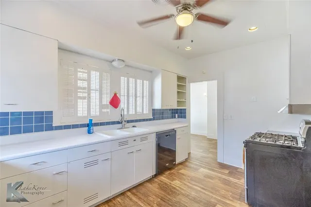a kitchen with stainless steel appliances granite countertop a sink cabinets and wooden floor