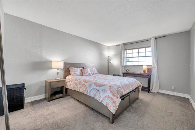 a spacious bedroom with a bed and a lamp