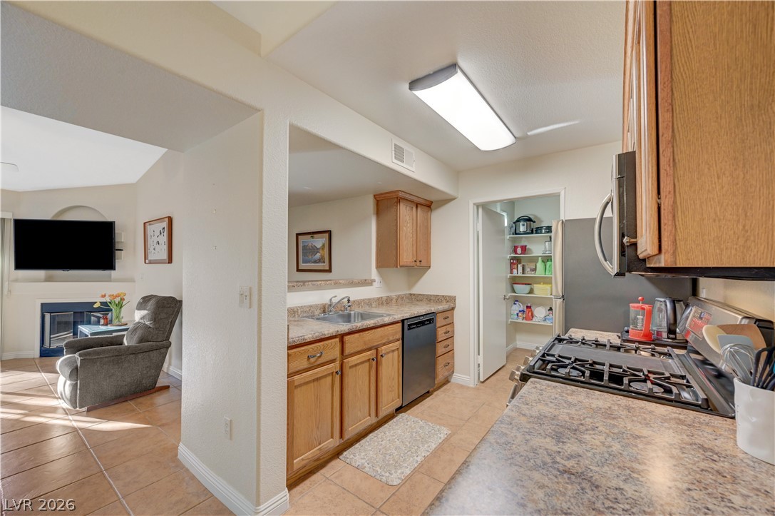 7885 West Flamingo Road, Unit 1071 Las Vegas, NV 89147 - Photo 11 of 28 Functional kitchen with ample counter space and convenient pantry access connects to a cozy living area.