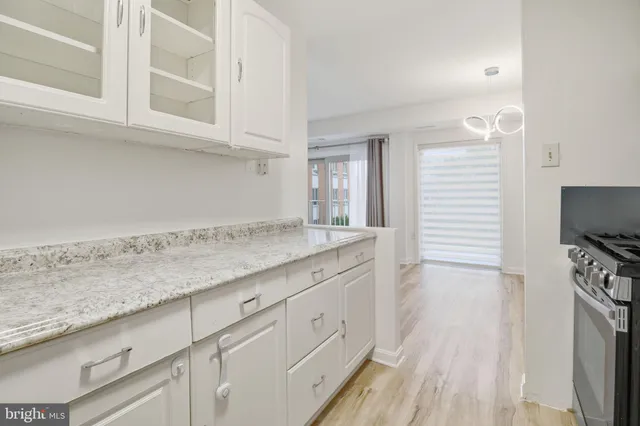 a kitchen with granite countertop white cabinets and a wooden floor