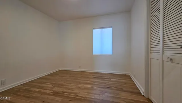 a view of a room that has wooden floor and a window