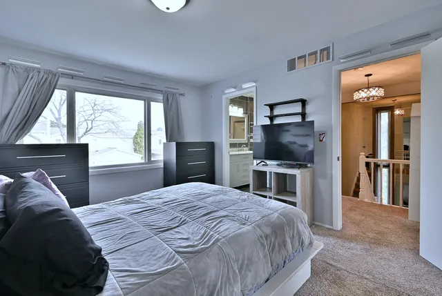 a bedroom with a large bed and a flat tv screen