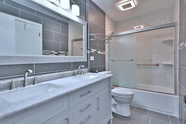 a bathroom with a granite countertop sink a toilet and shower