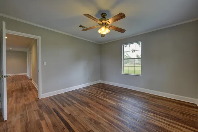 an empty room with wooden floor and a ceiling fan