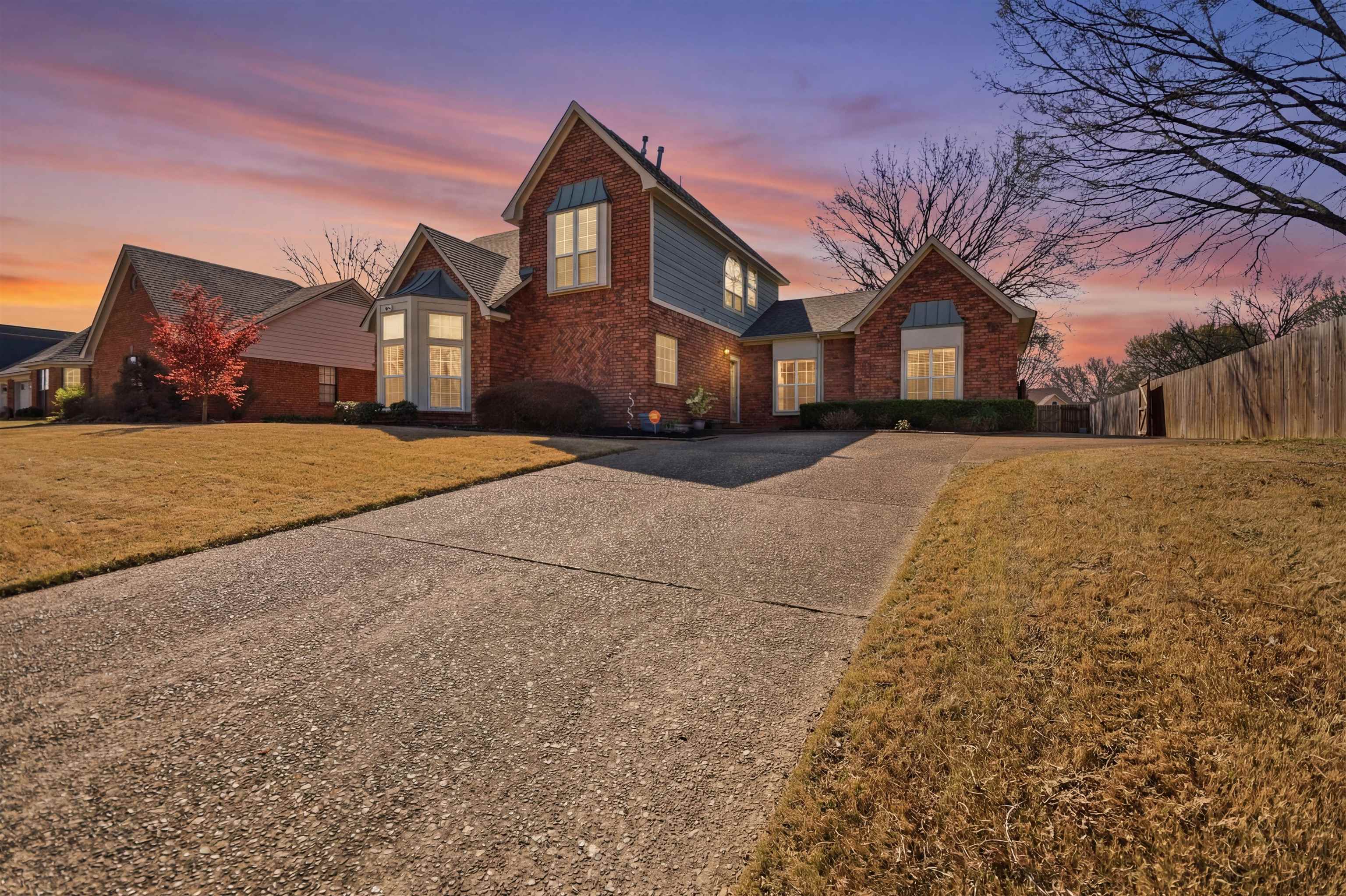 Traditional home featuring driveway and brick siding
