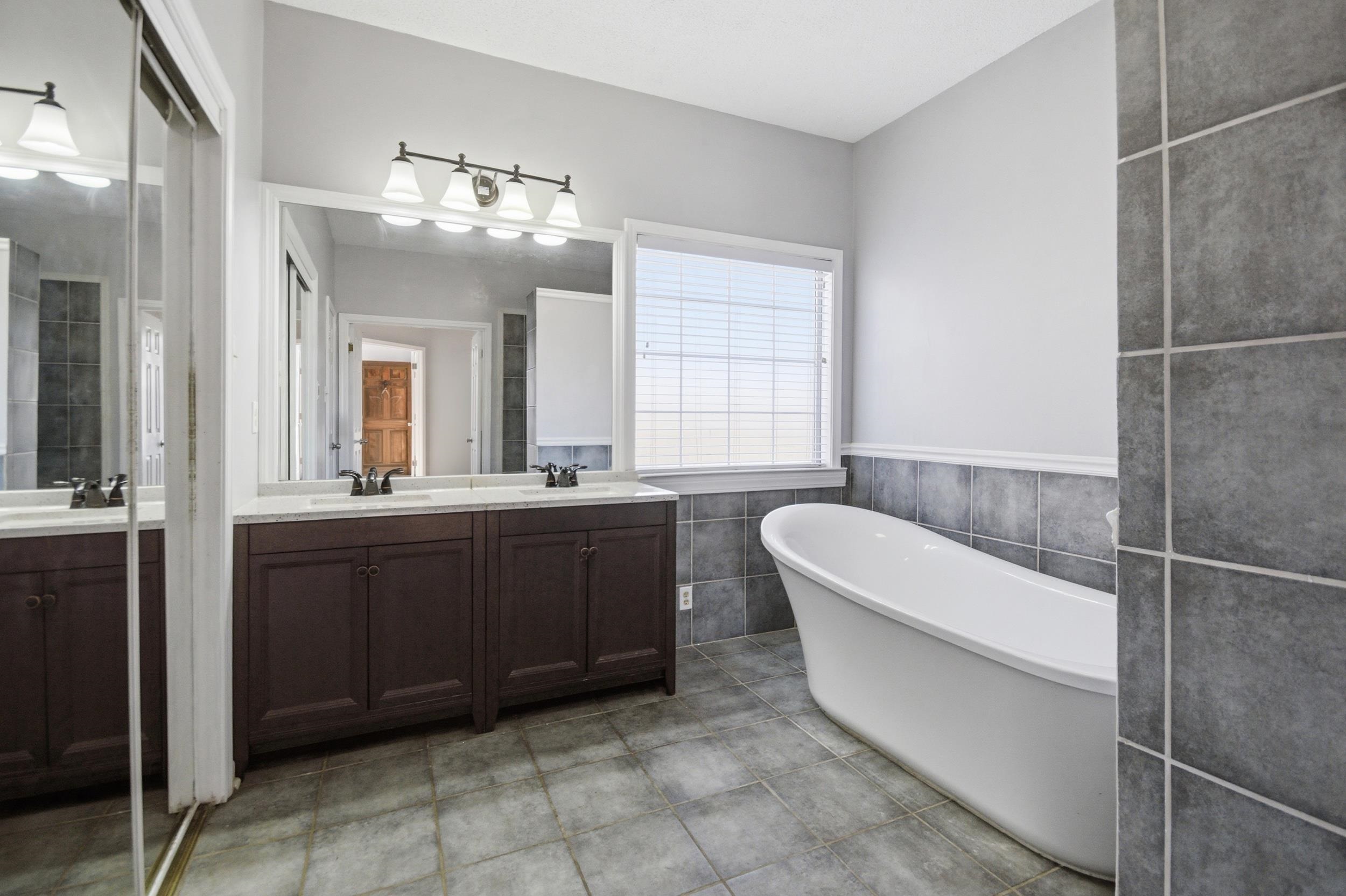 6605 Stephan Ridge Cove Bartlett, TN 38135 - Photo 14 of 30 Full bath with double vanity, a freestanding bath, tile walls, and light tile patterned floors
