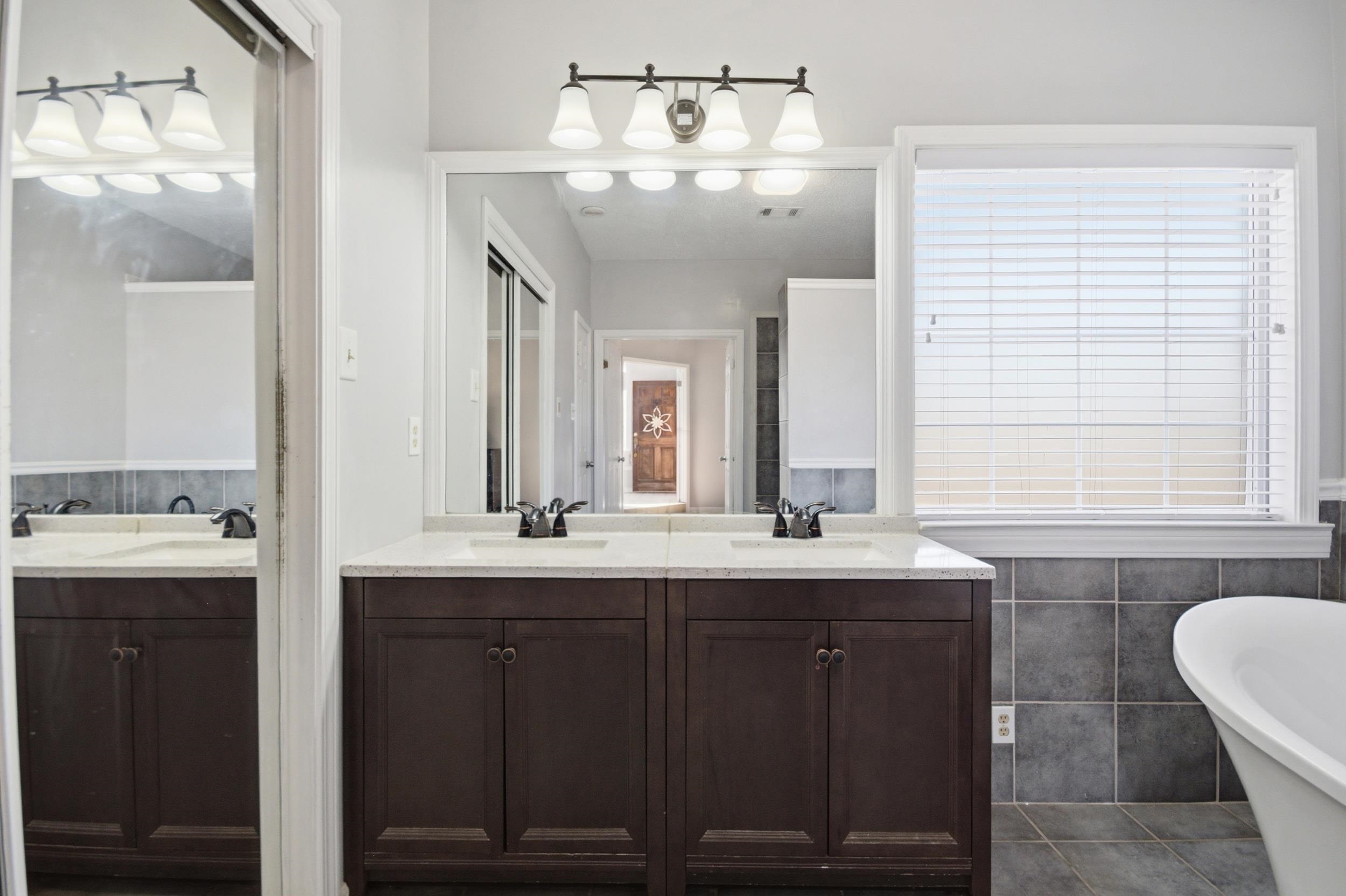 6605 Stephan Ridge Cove Bartlett, TN 38135 - Photo 15 of 30 Bathroom featuring double vanity, a freestanding bath, tile walls, and dark tile patterned flooring