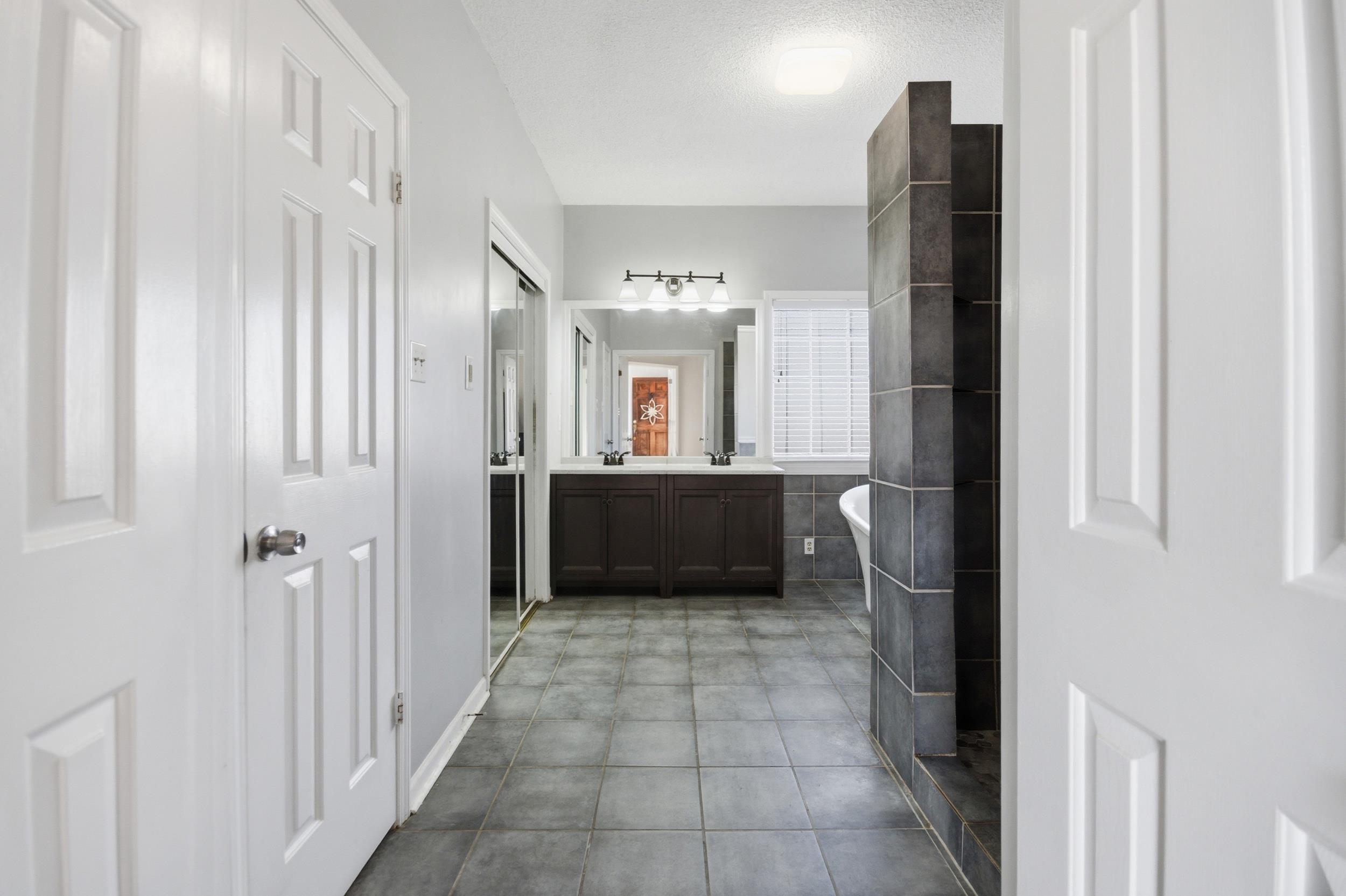 6605 Stephan Ridge Cove Bartlett, TN 38135 - Photo 17 of 30 Bathroom featuring double vanity, a freestanding bath, light tile patterned flooring, and a textured ceiling