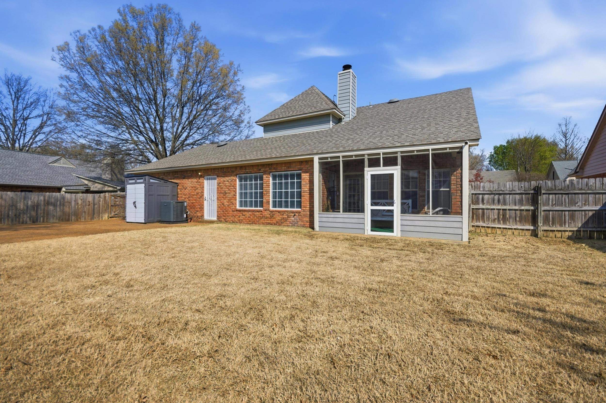 6605 Stephan Ridge Cove Bartlett, TN 38135 - Photo 30 of 30 Rear view of property featuring a fenced backyard, a storage shed, a chimney, roof with shingles, and a sunroom