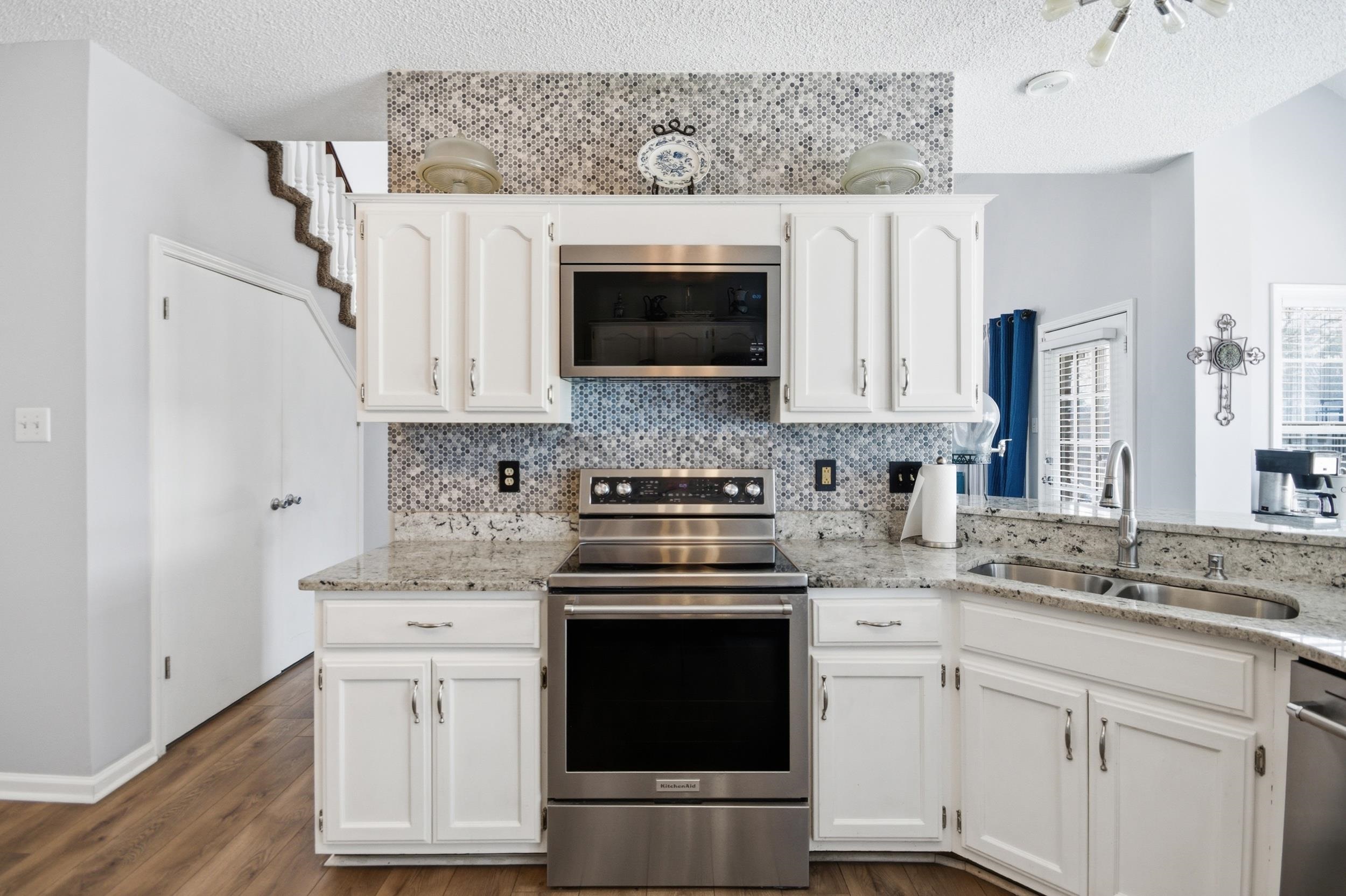6605 Stephan Ridge Cove Bartlett, TN 38135 - Photo 4 of 30 Kitchen featuring stainless steel appliances, light stone countertops, white cabinets, and a textured ceiling