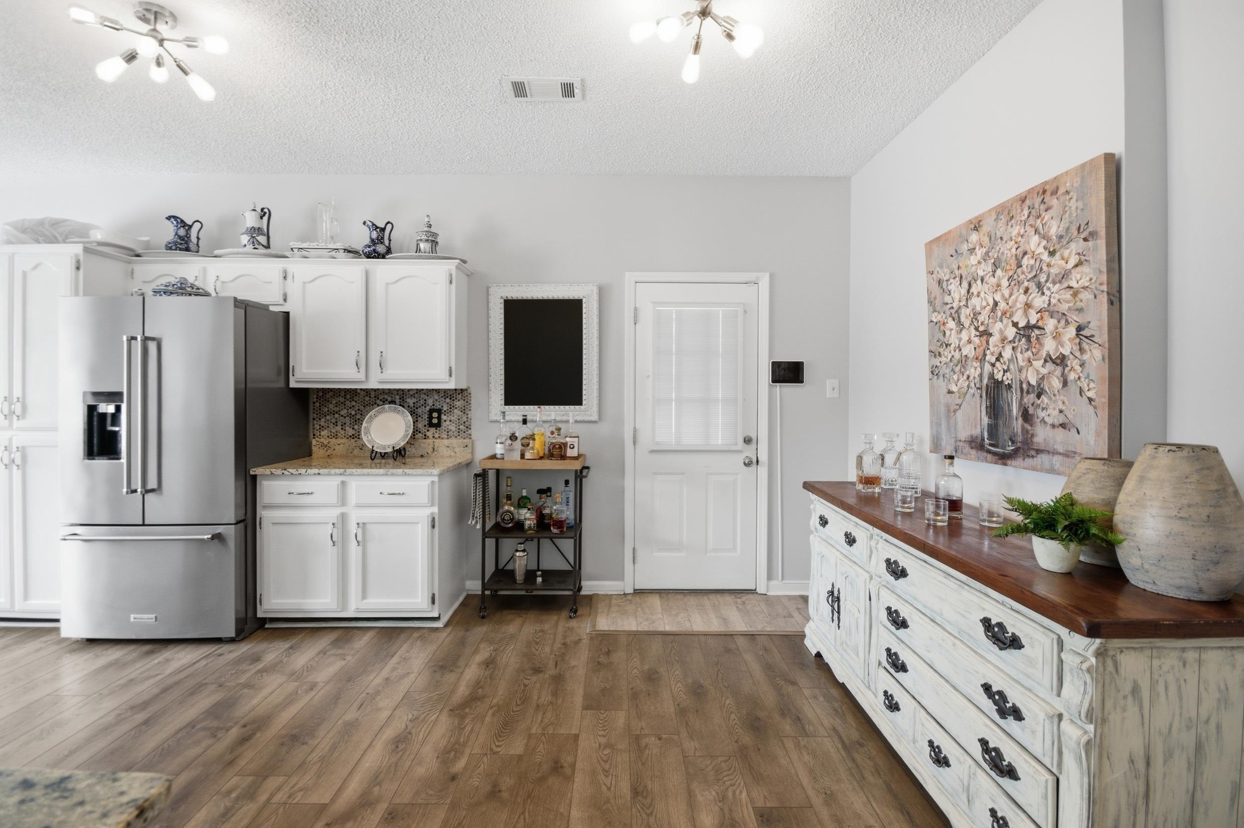 6605 Stephan Ridge Cove Bartlett, TN 38135 - Photo 6 of 30 Kitchen with high quality fridge, white cabinetry, dark wood-style floors, tasteful backsplash, and a textured ceiling