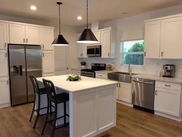 a kitchen with stainless steel appliances kitchen island a table chairs sink refrigerator and microwave