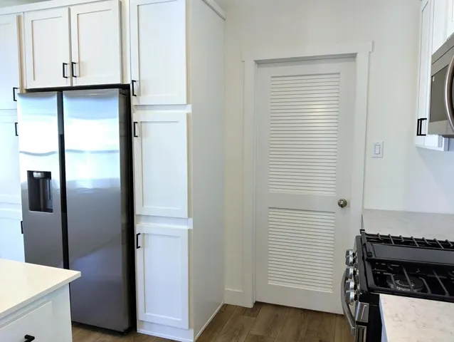 a kitchen with a refrigerator and white cabinets