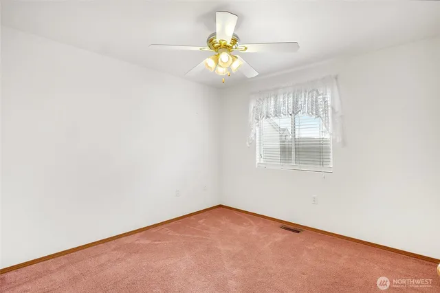 an empty room with a chandelier fan and a bathroom