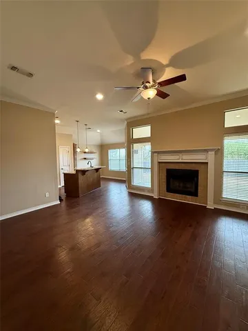 an empty room with fireplace wooden floor chandelier fan and windows