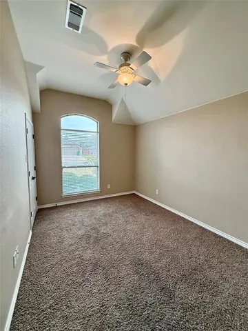 an empty room with a chandelier fan and windows