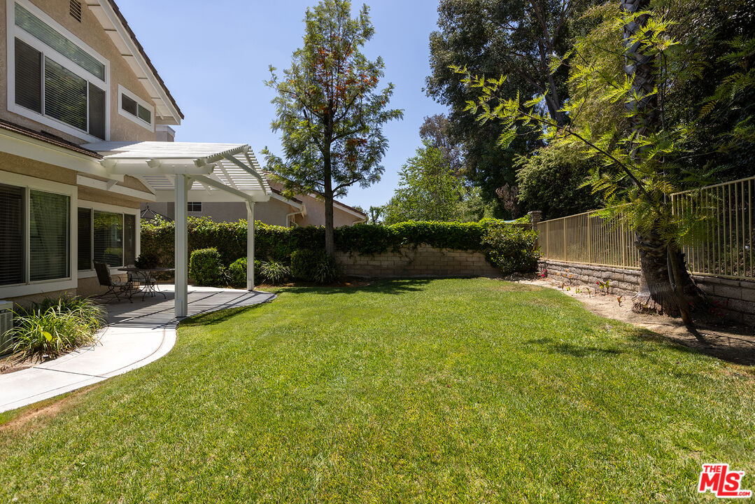 27050 Riversbridge Way Valencia, CA 91354 - Photo 21 of 37 a view of a patio with table and chairs under an umbrella