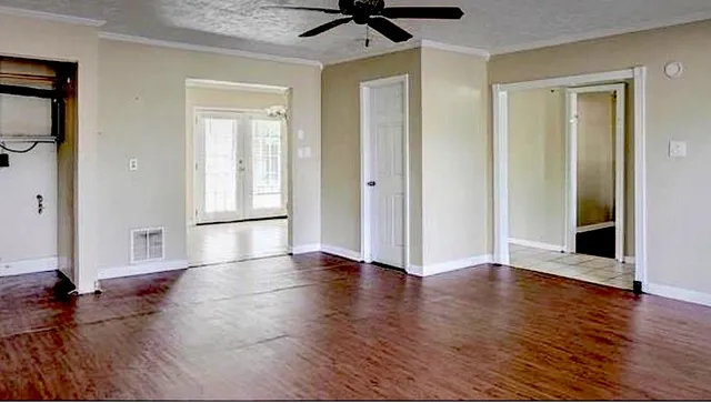 an empty room with wooden floor and a ceiling fan