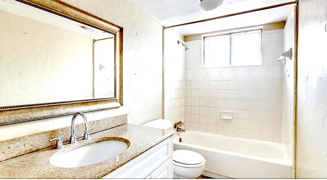 a bathroom with a granite countertop sink toilet and shower