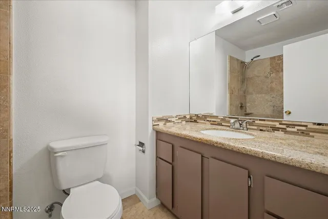 a bathroom with a granite countertop toilet sink and mirror