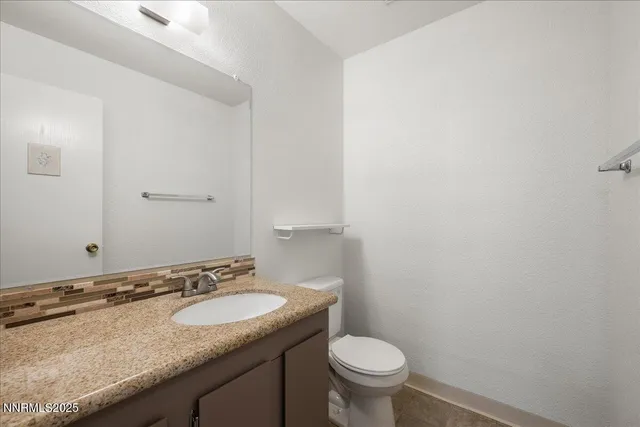 a bathroom with a granite countertop sink and a toilet