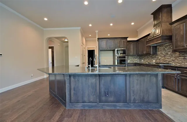 a kitchen with stainless steel appliances granite countertop a sink a stove and a wooden floors