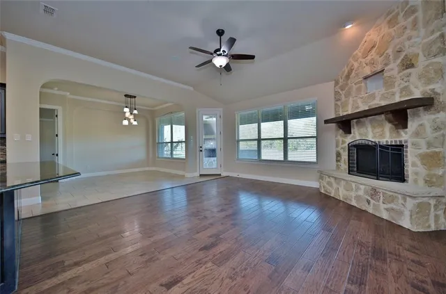 an empty room with wooden floor fireplace and windows