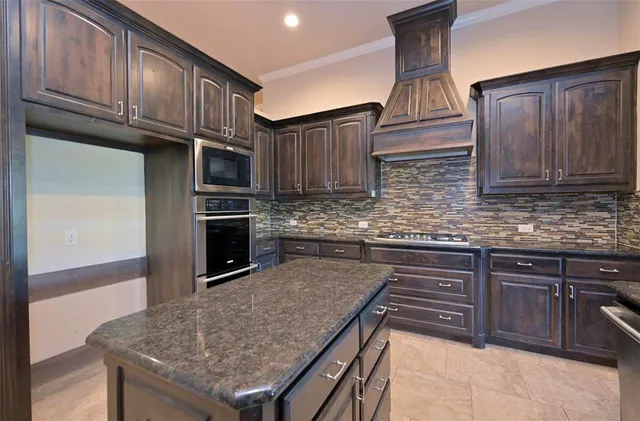a kitchen with stainless steel appliances granite countertop wooden cabinets a stove top oven a sink and dishwasher