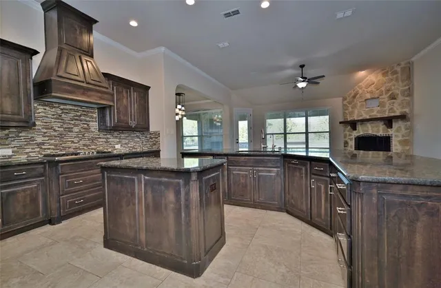 a kitchen with stainless steel appliances granite countertop a sink a stove and a wooden cabinets