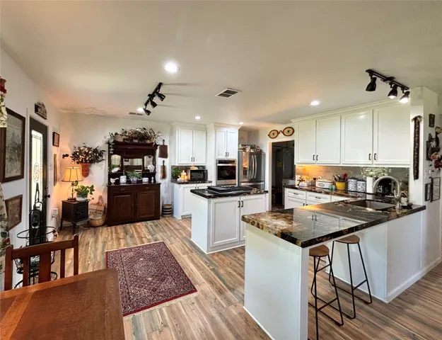 a kitchen with a refrigerator a stove top oven a sink dishwasher and white cabinets with wooden floor