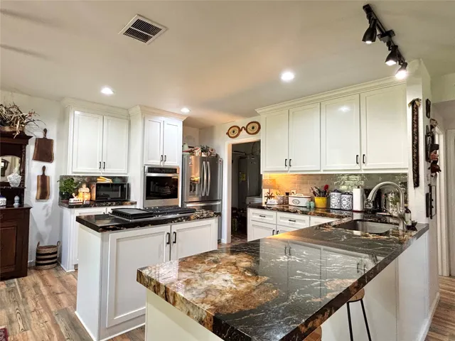 a kitchen with stainless steel appliances granite countertop a sink stove and refrigerator