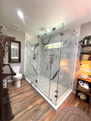 a spacious bathroom with a glass shower door and a window