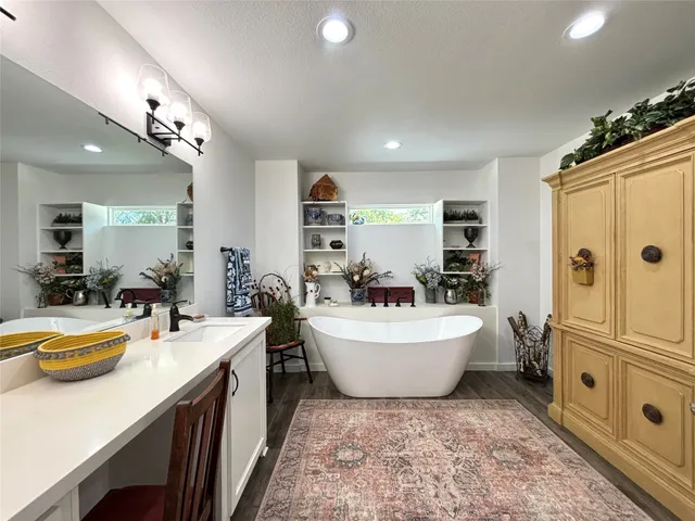 a bathroom with a tub sink double vanity and mirror