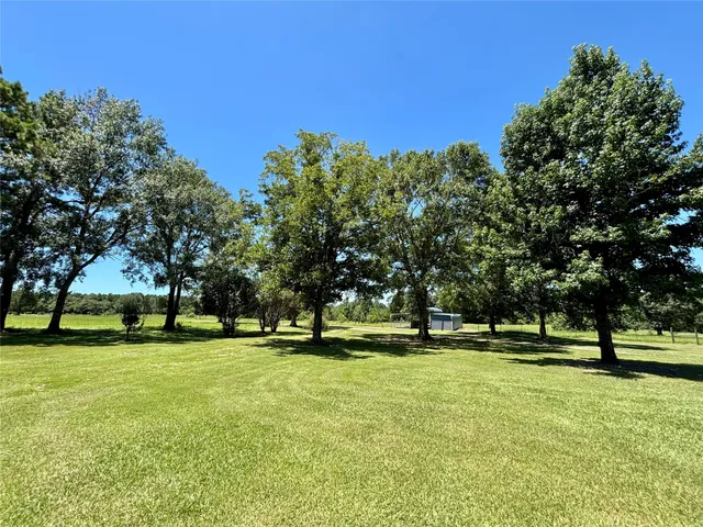 a big yard with lots of green space and trees in the background