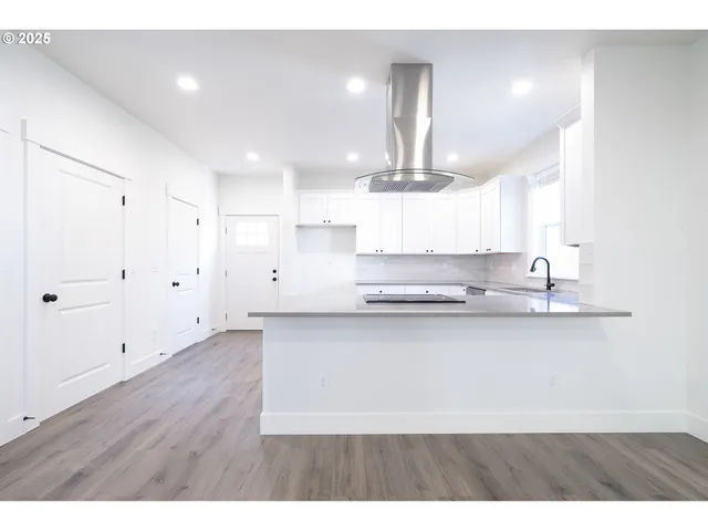 a large white kitchen with lots of counter space wooden floor and appliances