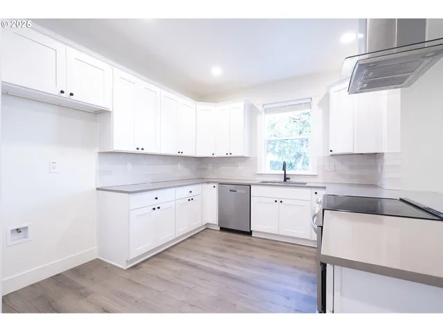 a kitchen with cabinets appliances a sink and a window