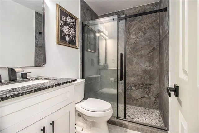 a bathroom with a granite countertop sink toilet and shower