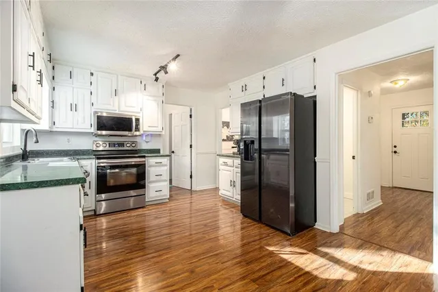 a kitchen with granite countertop a refrigerator and a stove top oven