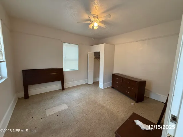 an empty room with a fireplace and a ceiling fan