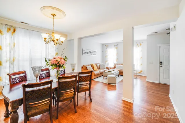 a dining room with furniture a chandelier and wooden floor