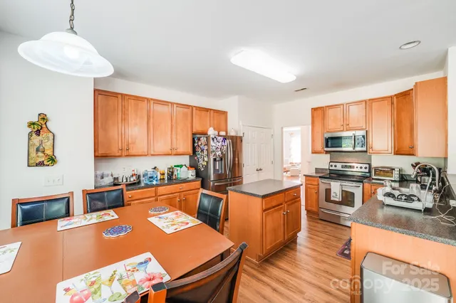 a kitchen with stainless steel appliances granite countertop a stove a sink dishwasher and a refrigerator with wooden floor