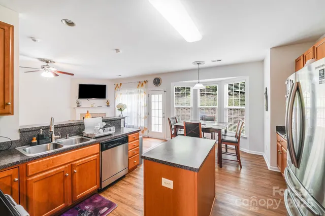 a dining hall with stainless steel appliances granite countertop a sink a stove and refrigerator