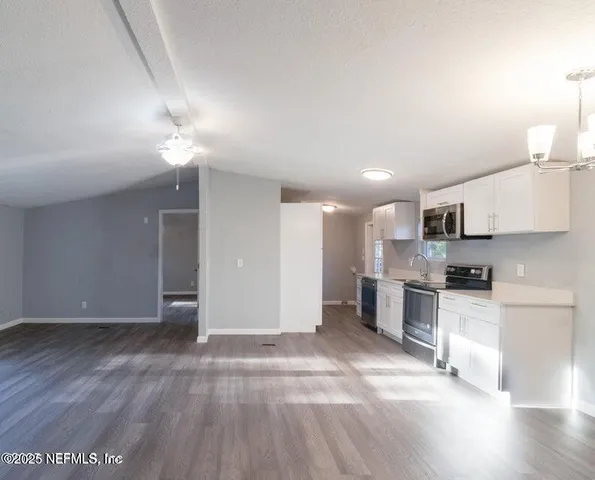a view of a kitchen with a sink and dishwasher a stove top oven with wooden floor