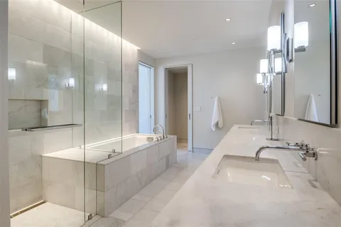 a bathroom with a sink double vanity granite tub shower and a mirror